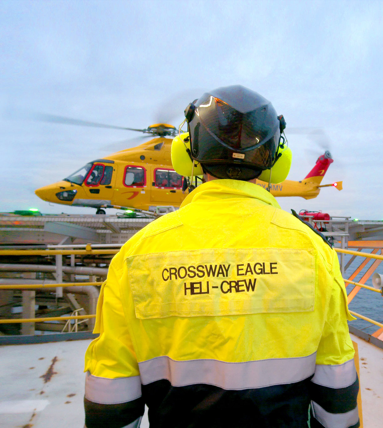 Man from behind on rig platform with helicopter in background